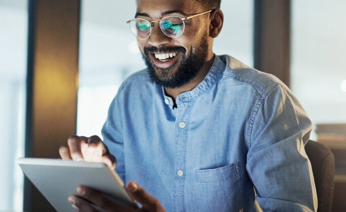 A man smiling while looking at this tablet